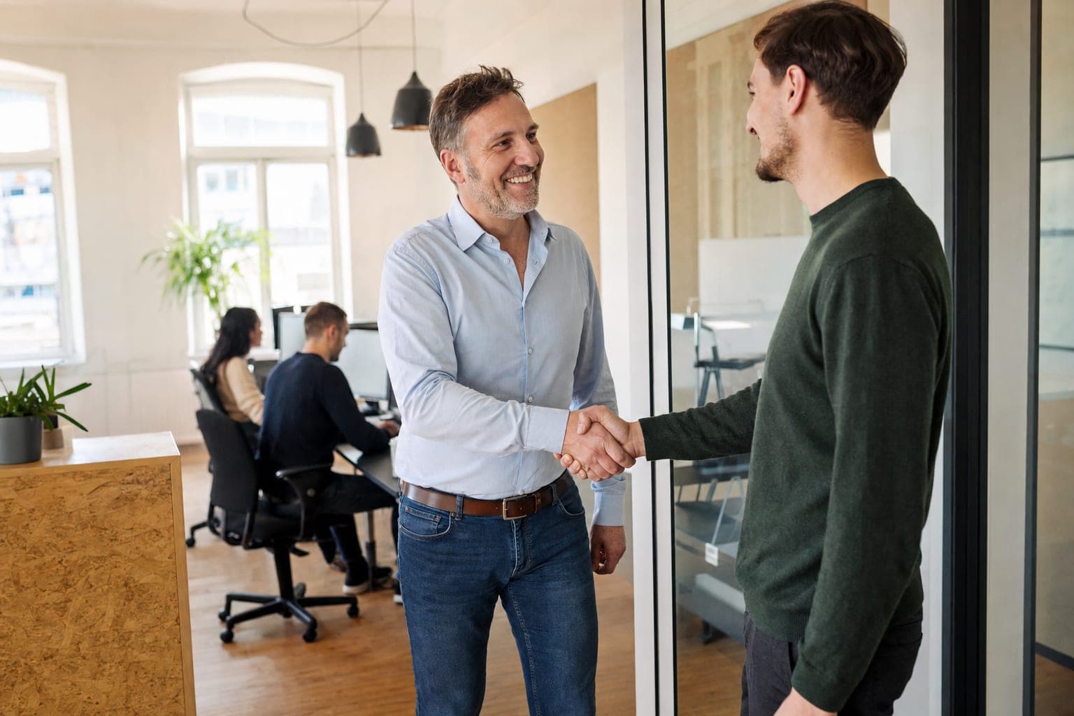 Geschäftsführer begrüßt eine neue Mitarbeiterin per Handschlag
